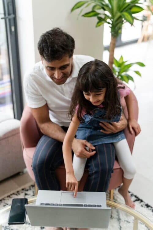 Father sitting with daughter and using laptop - CurioBuddy Father sitting with daughter and using laptop to explore CurioBuddy website for school age children at home. CurioBuddy provides a safe and secure platform for primary school to middle school students for curiosity and creativity along with collaborative learning through its community that reinforces classroom knowledge. Subscribe to children's magazines with CurioBuddy.